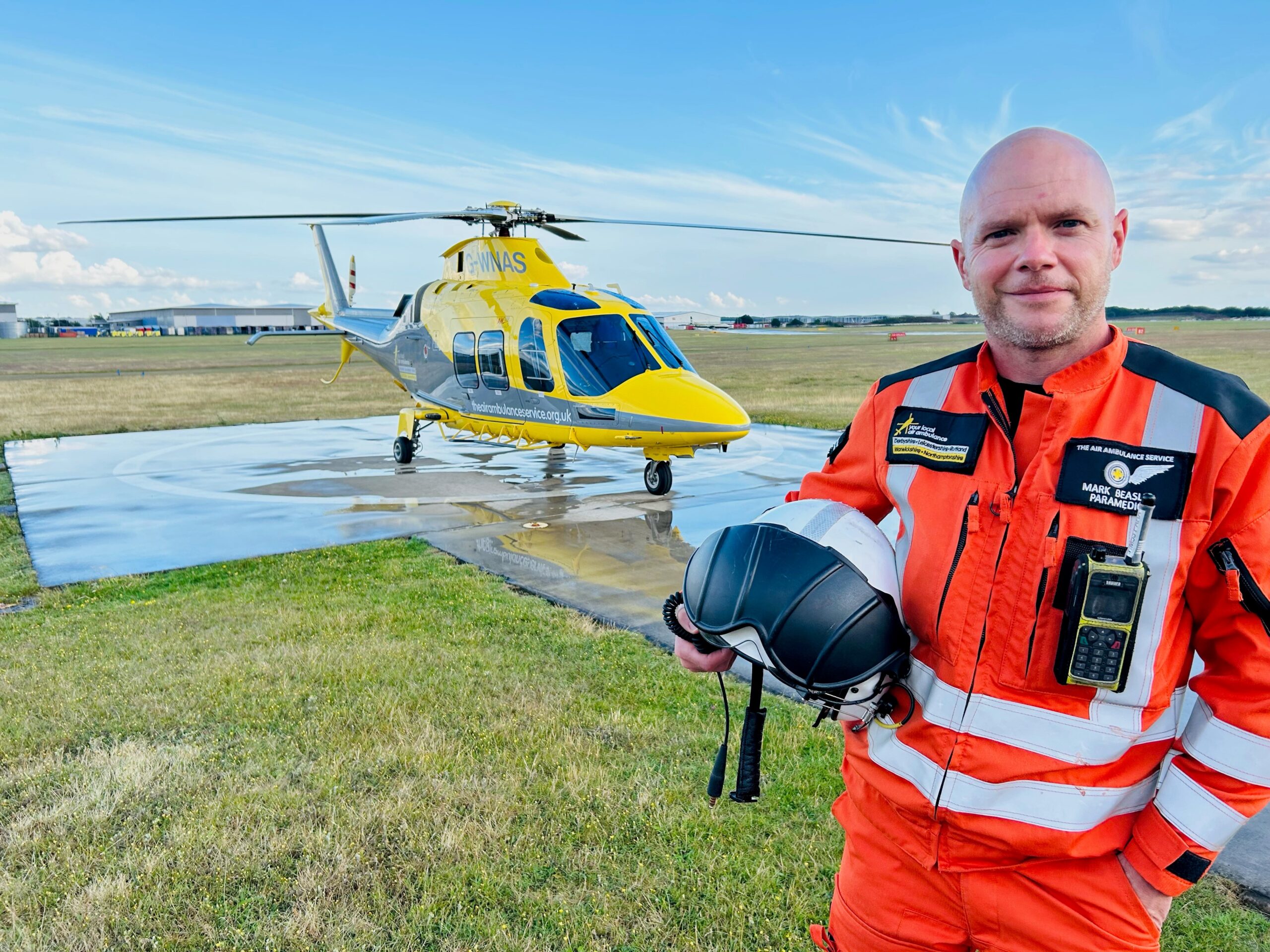 Mark Beasley, Critical Care Paramedic, stood in front of a HEMS helicopter.