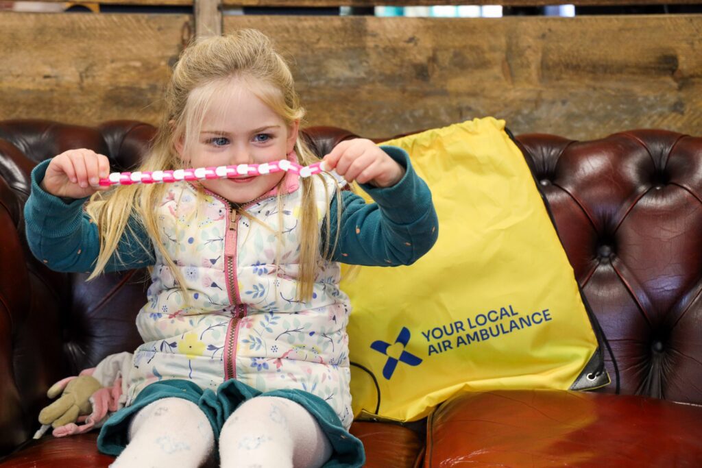 A little girl sitting on a sofa playing with a fidget toy from our Sensory Bag.