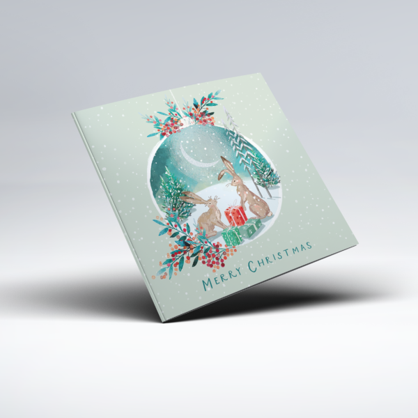 Illustrated Christmas card showing two brown hares sitting beside red and green wrapped presents within a bauble, decorated with leaves and red berries. White snowflakes fall across a soft pale green background, with "Merry Christmas" below the scene.