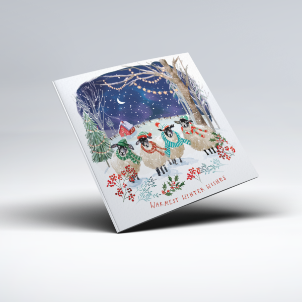 Illustrated Christmas card showing four sheep standing in snow and wearing colourful knitted hats and scarves beneath trees strung with glowing lights. Snow-covered fir trees, a crescent moon, a small red house, holly and winter berries surround the scene, with "Warmest Winter Wishes" below.