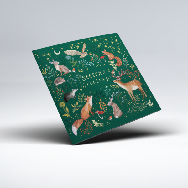 Decorative illustrated Christmas card on a dark green background featuring woodland animals including a deer, foxes, hares, a hedgehog, squirrel and birds among leaves, flowers, mushrooms and berries. Golden stars and a crescent moon fill the background, with "Season's Greetings" in the centre.
