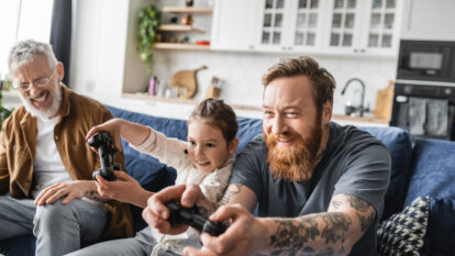 Tattooed dad playing video game with daughter