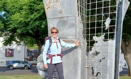 Anne Stephenson, a fundraiser, in front of the starting point monument at Minehead, Somerset.