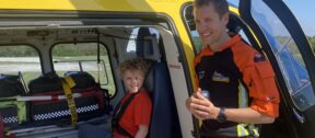Charlie during a base visit, sitting in the helicopter, with the crew standing to him.