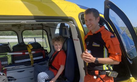 Charlie during a base visit, sitting in the helicopter, with the crew standing to him.