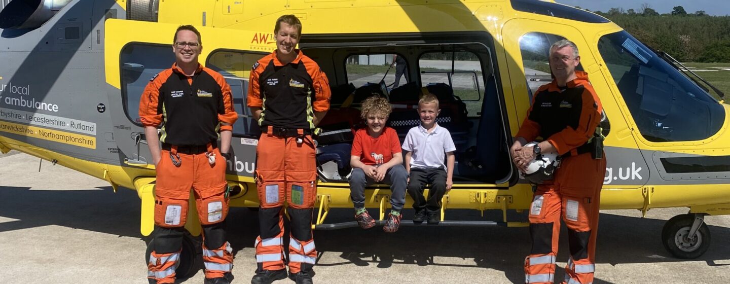 Charlie and his brother during a base visit, sitting in the helicopter, with the crew standing to him.