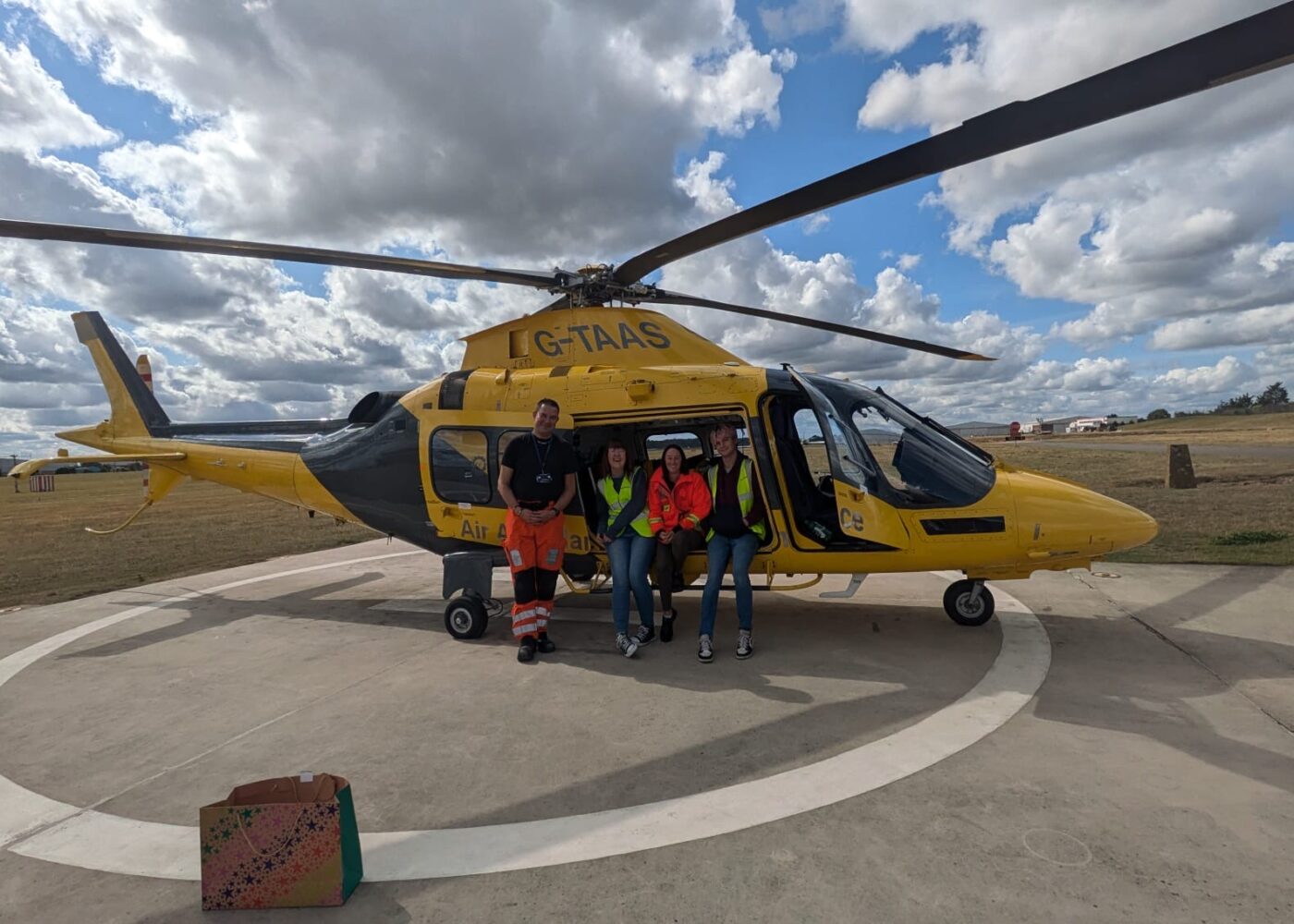 Rachael on a base visit, with The Air Ambulance crew, in front of a helicopter.