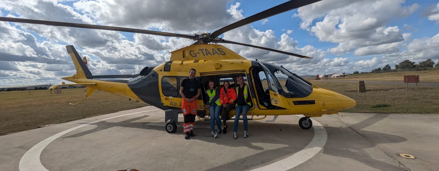 Rachael on a base visit, with The Air Ambulance crew, in front of a helicopter.