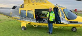 John Murphy on a base visit, standing in front of a helicopter.
