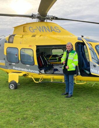 John Murphy on a base visit, standing in front of a helicopter.