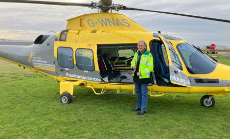 John Murphy on a base visit, standing in front of a helicopter.