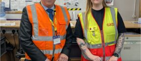 GXO Logistics staff stand either side of a framed and signed Doncaster Rovers FC shirt.