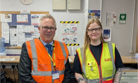 GXO Logistics staff stand either side of a framed and signed Doncaster Rovers FC shirt.