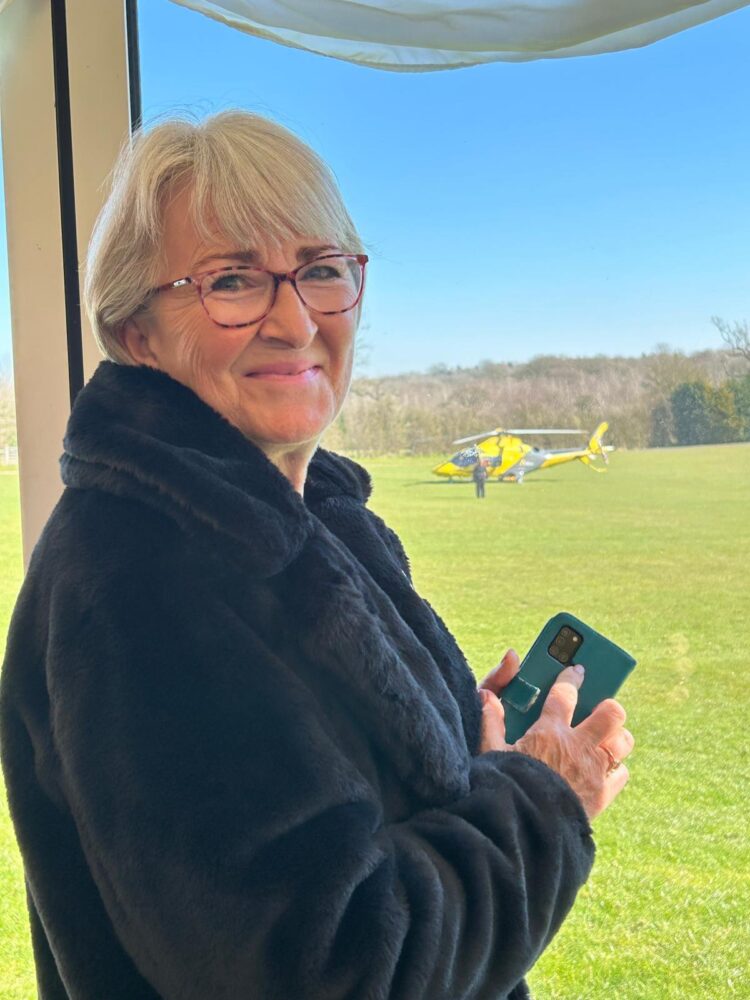 Woman smiling wearing black coat with window and helicopter in background