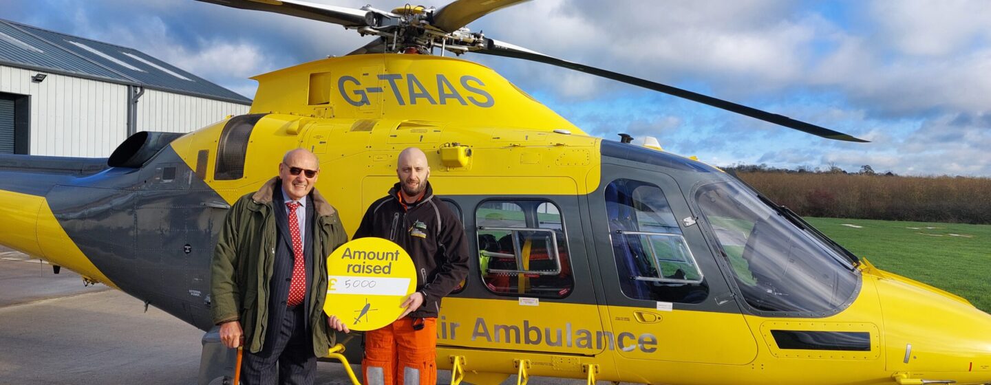 John Mills and our crew member standing in front of our helicopter at our air base.