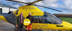 John Mills and our crew member standing in front of our helicopter at our air base.