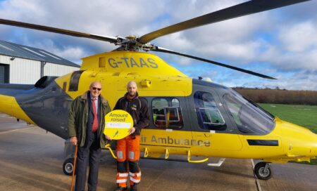John Mills and our crew member standing in front of our helicopter at our air base.