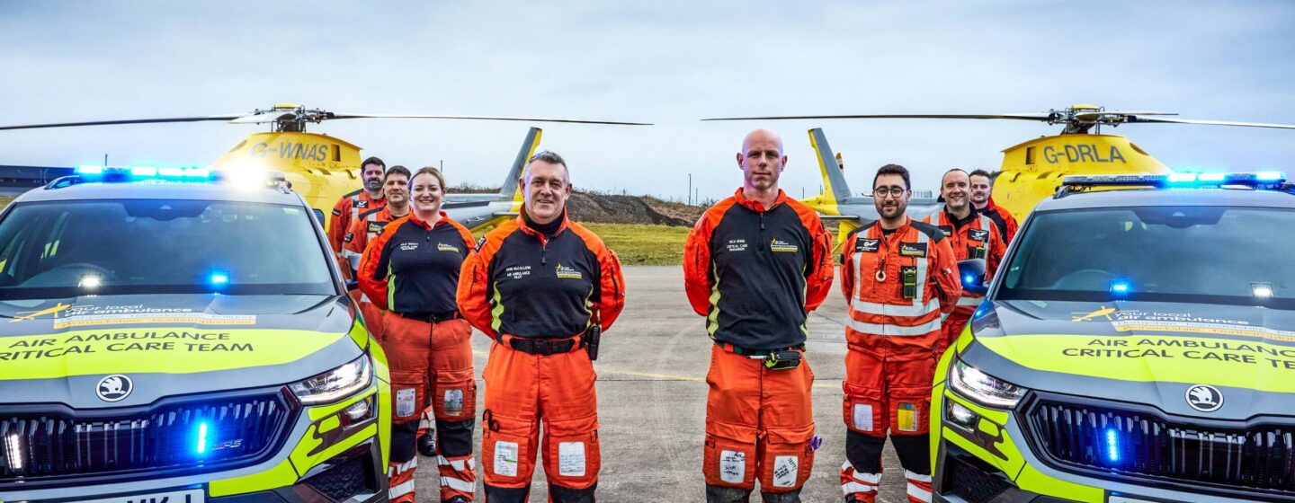 A groupshot of some of our crew with two of our critical care cars and two of our helicopters in the background.