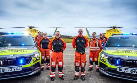 A groupshot of some of our crew with two of our critical care cars and two of our helicopters in the background.