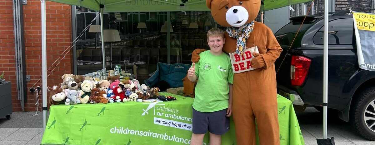 Jack standing in front of his fundraising stall with a bear