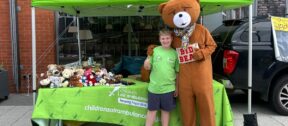 Jack standing in front of his fundraising stall with a bear