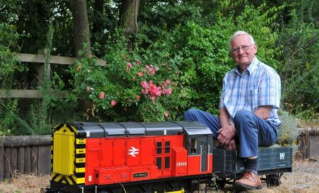 Richard sitting on his model train in his garden