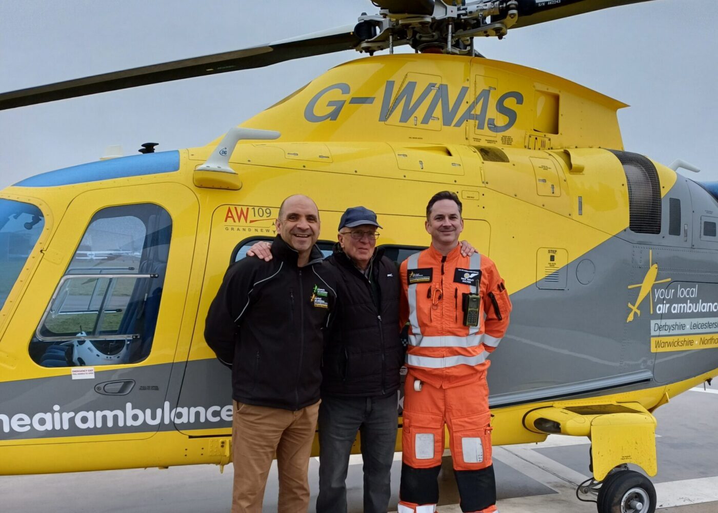 Stephen on a base visit, standing with the crew who saved his life, in front of the helicopter.