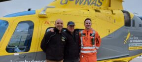 Stephen on a base visit, standing with the crew who saved his life, in front of the helicopter.