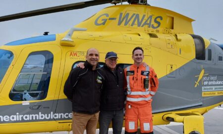 Stephen on a base visit, standing with the crew who saved his life, in front of the helicopter.