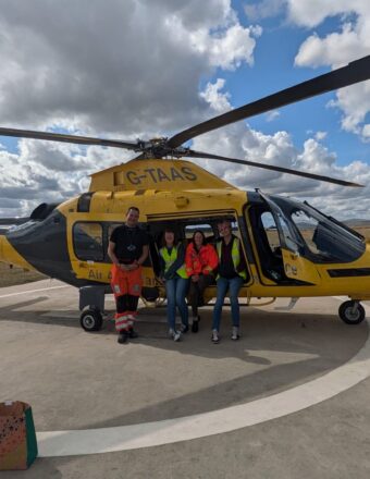 Rachael on a base visit, with The Air Ambulance crew, in front of a helicopter.