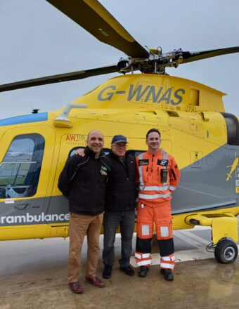 Stephen on a base visit, standing with the crew who saved his life, in front of the helicopter.