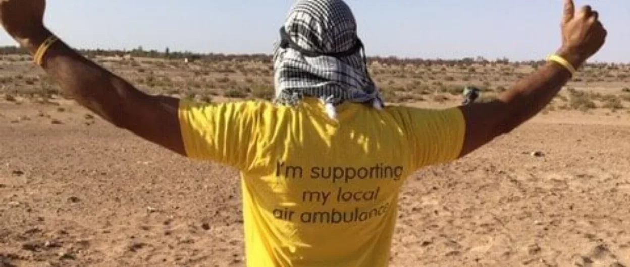 person with back to camera in desert wearing your local air ambulance tshirt